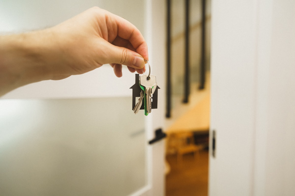 A hand holding a set of keys at an open front door