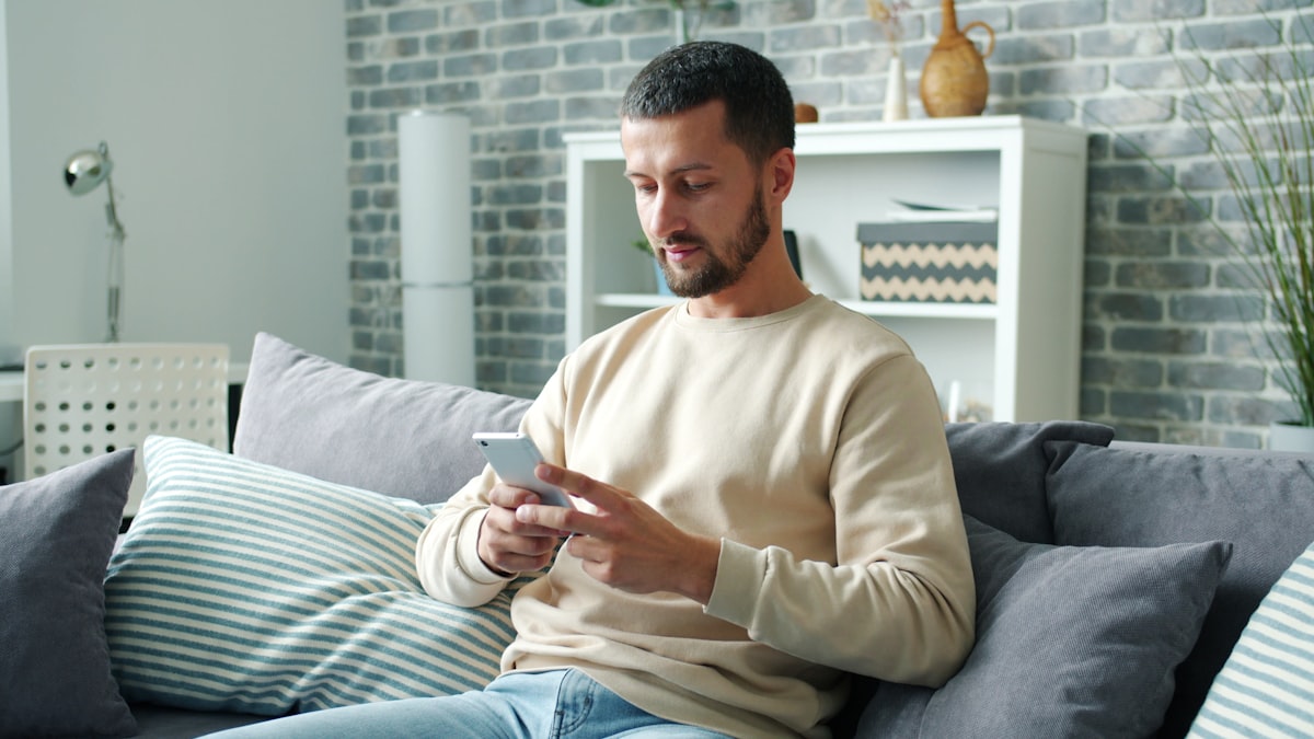 A tenant relaxing on his sofa at home, looking at his phone